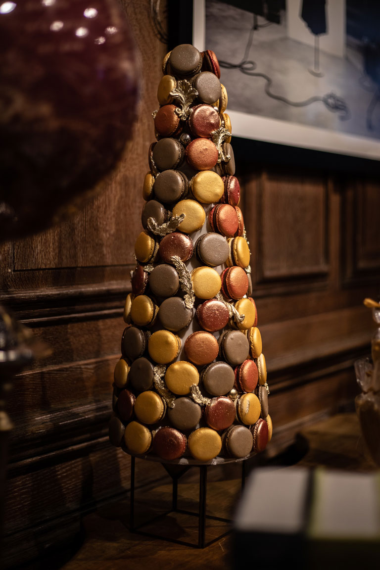 A luxurious macaron tower with brown macarons, dark red macarons, gold macarons and bronze macarons